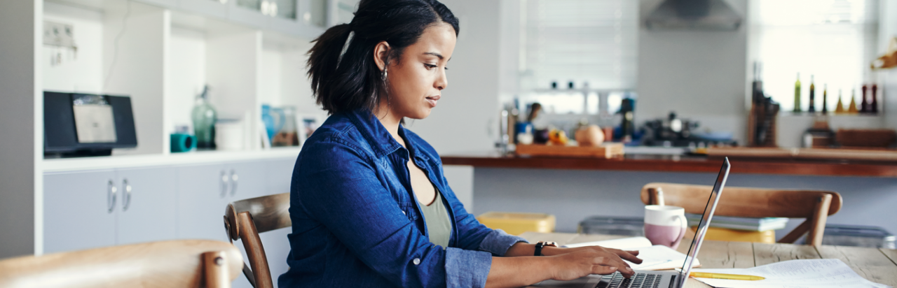 Woman sitting at table and typing on a laptop computer